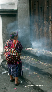 Una donna maya prega di fronte alla porta della chiesa di Chichicastenango, Guatemala. Sciamanesimo. Curanderismo.